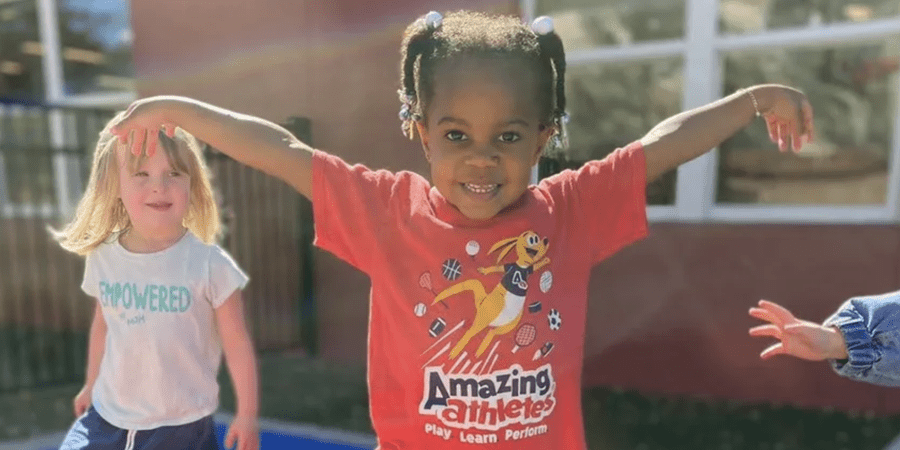 Little girl smiles for the camera in Amazing Athletes shirt